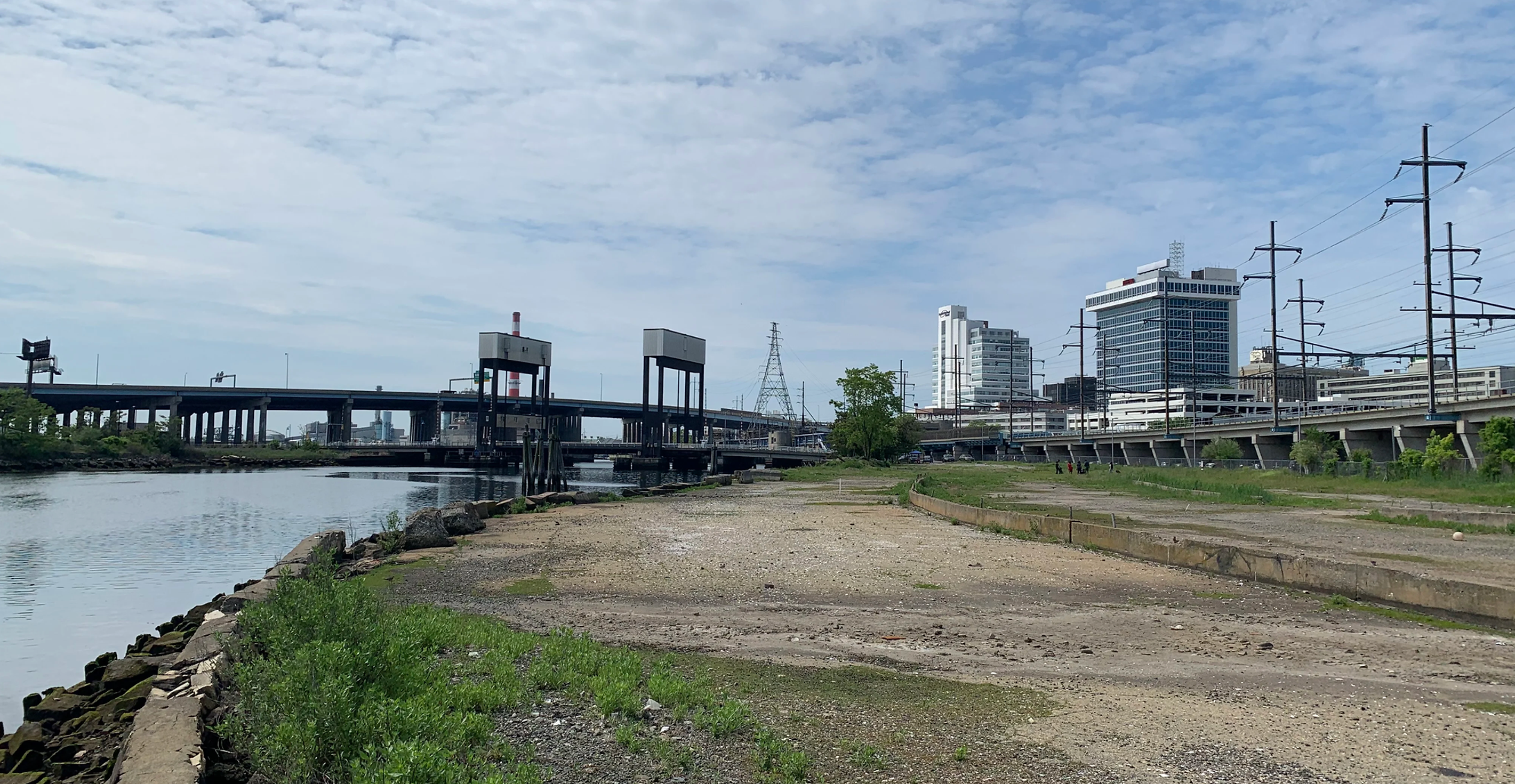 view of empty lot with bridge and buildings in the background
